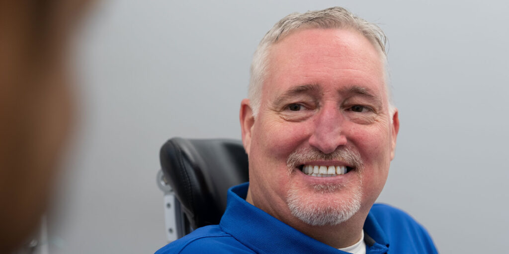 smiling dental patient man blue shirt hero